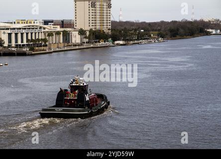 Savannah, Georgia, USA - 20. Februar 2024: Ein Schlepper schiebt an einem klaren Nachmittag durch den Savannah River, vorbei an den Gebäuden der Innenstadt von Savannah. Stockfoto