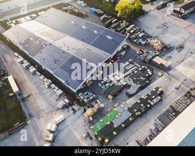 Aus der Vogelperspektive einer Fabrik, einer Lagerhalle in den Vororten mit Dach, das mit Solarpaneelen bedeckt ist. Stockfoto