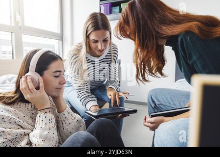 Gruppe von drei Mitbewohnern, College Studentin, junge kaukasische Frauen, verbringen Zeit zusammen in ihrem Zimmer, lernen, reden, Spaß haben, lachen Stockfoto