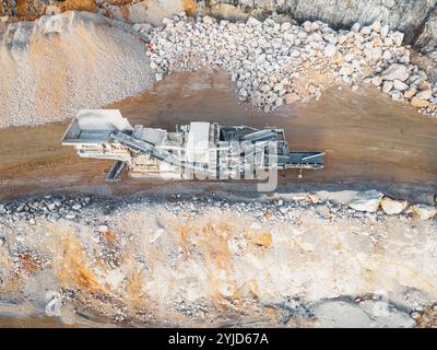Aus der Vogelperspektive des Tagebaubruchs mit schweren Maschinen, die auf dem Gelände arbeiten. Bagger und Lkw fahren auf dem Gelände. Sonniger Tag auf dem Land Stockfoto