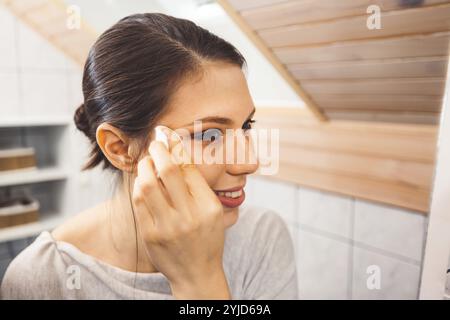 Schöne junge Frau, die ihr Gesicht reinigt, das Make-up mit einem Wattepad und mizellarem Wasser entfernt. Hautpflege und Schönheit. Junge schöne Frau putzt h Stockfoto