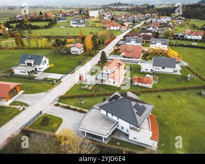 Luftaufnahme, Drohne fliegt über neue Wohnsiedlungen auf der Landseite. Einfamilienhäuser in den Vororten umgeben von Wald und grünen Feldern Stockfoto