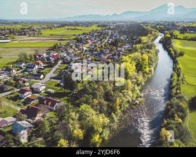 Luftaufnahme, Drohne fliegt über Vorstadtgemeinde auf dem Land. Einfamilienhäuser in den Vororten umgeben von Wald und grünen Feldern Stockfoto