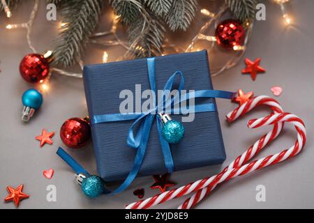 Weihnachtsgeschenke für Herren. Dunkelblaue Geschenkbox, Süßigkeiten auf weihnachtlichem Hintergrund. Geschenk der Zeit. Geschenk für Ehemann. Geschenk für ihn. Modell, Kopierraum Stockfoto