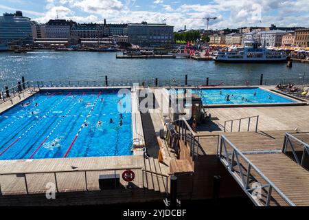 Gäste genießen am sonnigen Sommertag im Stadtzentrum von Katajanokanlaituri am 6. Juli 2024 in Helsinki, F, ein öffentliches Schwimmbad und eine traditionelle Sauna Stockfoto