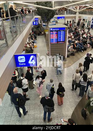 Überfüllte Abflug-Lounge am Flughafen Bristol mit Personen, die auf ihren Flug und die Gate-Nummer warten, die auf der Tafel angezeigt werden Stockfoto