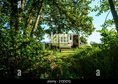 Ein Camper steht in idyllischer Umgebung im Sommer auf einer Wiese zwischen Bäumen, Vogesen, Frankreich. Mit einem Campervan unterwegs *** Ein Wohnmobil steht im Sommer in idyllischer Umgebung auf einer Wiese zwischen Bäumen, Vogesen, Frankreich unterwegs in einem Wohnmobil Stockfoto