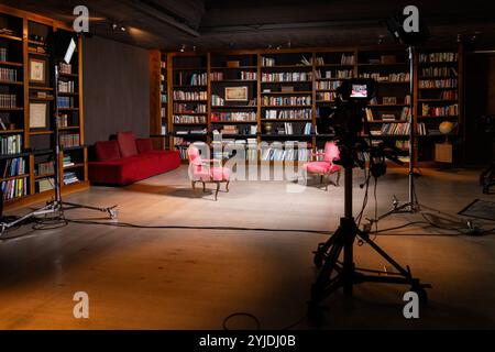 Professionelle Einrichtung im Innenbereich für ein TV-Interview mit Kameras und gemütlichen Stühlen in einer Bibliothek Stockfoto