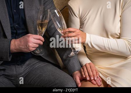 Stilvolles Paar, das Champagner hält und einen Urlaub feiert. Hände von Mann und Frau mit Brille Stockfoto