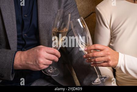 Stilvolles Paar, das Champagner hält und einen Urlaub feiert. Hände von Mann und Frau mit Brille Stockfoto