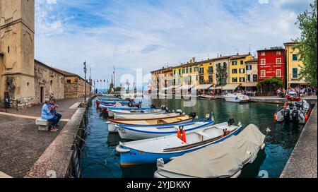 LAZISE, ITALIEN – 21. AUGUST 2024: Porto Lazise am Gardasee mit seiner historischen Uferpromenade, den ruhigen Gewässern und den am Kai angedockten Booten spiegelt das wider Stockfoto