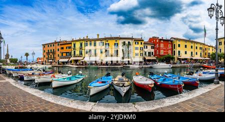 LAZISE, ITALIEN – 21. AUGUST 2024: Porto Lazise am Gardasee mit seiner historischen Uferpromenade, den ruhigen Gewässern und den am Kai angedockten Booten spiegelt das wider Stockfoto