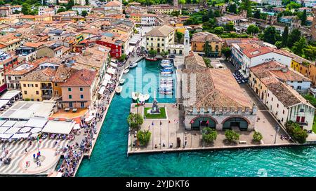 LAZISE, ITALIEN – 21. AUGUST 2024: Porto Lazise am Gardasee mit seiner historischen Uferpromenade, den ruhigen Gewässern und den am Kai angedockten Booten spiegelt das wider Stockfoto