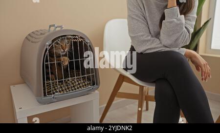 Eine Frau mit ihrer Katze in einem Träger, die im Innenraum einer Tierklinik wartet. Stockfoto