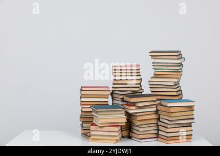 Viele Stapel von Lehrbüchern zum Studium in der Bibliothek auf grauem Hintergrund Stockfoto