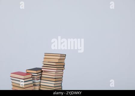 Viele Stapel von Lehrbüchern zum Studium in der Bibliothek auf grauem Hintergrund Stockfoto