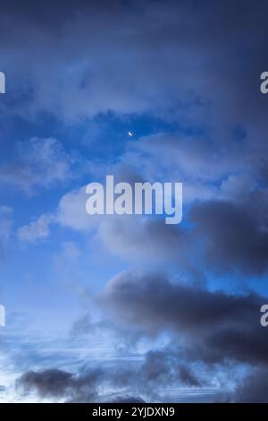 Blauer Himmel mit Wolken und schwindendem Mond Stockfoto