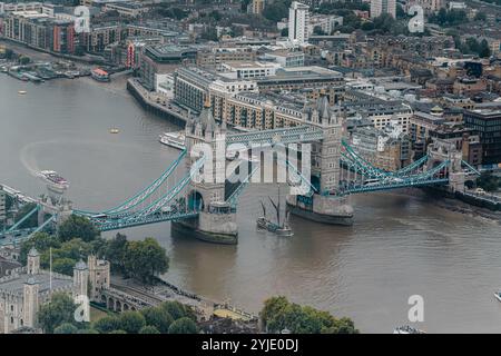 Ein Boot mit hohem Mastmast unterquert die erhöhte Tower Bridge, die 1894 fertiggestellt wurde und eines der bekanntesten Wahrzeichen Londons ist, City of London, UK Stockfoto