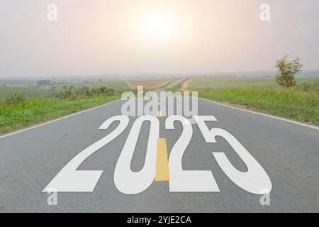 Neujahrstext 2025 geschrieben auf Asphaltstraße mit Blick auf junge Zuckerrohrplantage mit Sonnenuntergang Himmel, natürliche Landschaft mit Autobahn Stockfoto