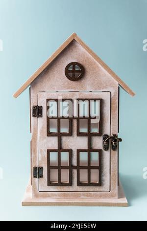Rustikaler Kerzenhalter handgefertigt. Holzhaus mit Fenstern auf blauem Hintergrund. Konzept-DIY Stockfoto