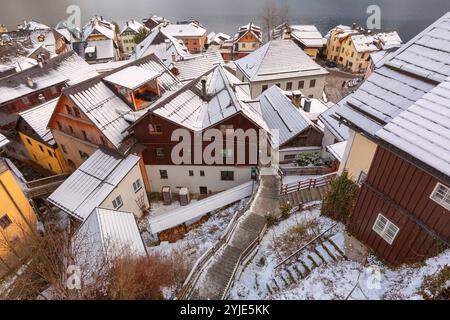 Blick aus der Vogelperspektive auf das Dorf Hallstatt im Winter: Schneebedeckte Dächer, traditionelle Almhäuser und schmale Wege, die den Hang hinunter zum See führen, Österreich Stockfoto