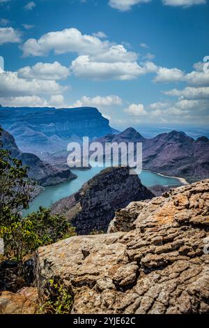 Eine atemberaubende Landschaft mit einem sich windenden Fluss durch den majestätischen Blyde River Canyon, mit zerklüfteten Klippen und einem lebendigen Himmel voller Wolken. Stockfoto