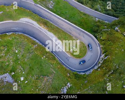 Zwei blaue Autos in Harpin-Kurve auf der Bergstraße in den Schweizer alpen von oben, Luftdrohne geschossen Stockfoto