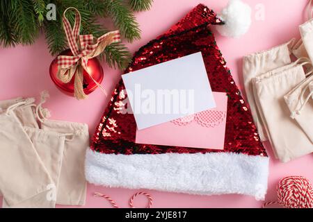 Eine Postkarte mit pinkfarbenen Umschlägen, einem Adventskalender und festlichen Weihnachtsdekorationen auf hellrosa Hintergrund. Stockfoto