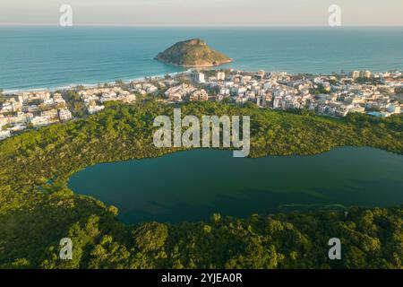 Blick aus der Vogelperspektive auf einen See in einem Park und Häuser vor dem Strand mit Pontal Rock im Ozean in Rio de Janeiro Stockfoto