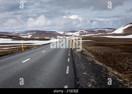 Ringstraße (Route 1) gerade Asphaltstraße in Ost-Island mit kargen vulkanischen Bergen bedeckt mit Schnee, gelbe Straßenmarkierungen an den Seiten. Stockfoto