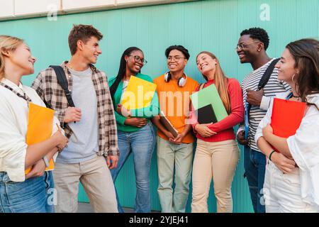 Eine vielfältige Gruppe von Studenten, die sich im Freien unterhalten und lächeln, junge Freunde, die Notizbücher und Rucksäcke halten, Kontakte knüpfen und Gespräche genießen, glückliche multikulturelle College-Gruppe, die an der Universität steht. Hochwertige Fotos Stockfoto