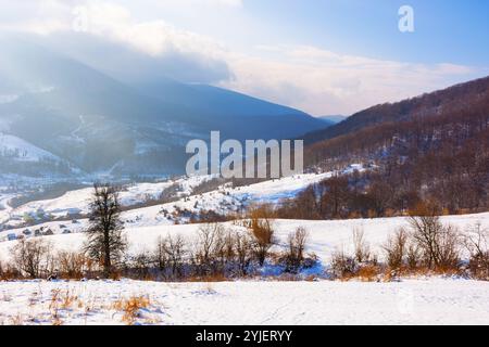 Berglandschaft im Winter. Trübes Wetter mit Wolken am Himmel. Blattlose Bäume auf den schneebedeckten Hängen Stockfoto