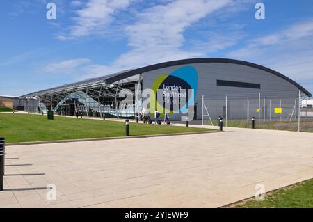 Flughafen London Southend. Passagiere mit Gepäck, die in Richtung des Terminalgebäudes fahren, mit dem London Southend Airport Logo und dem Symbol Stockfoto