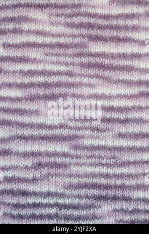 Nahaufnahme von handgefertigtem Stricktuch in weichen, angenehmen Farben mit Streifenmuster aus verlaufendem Wollgarn. Fügt Textur zusammen. Abstrakter Hintergrund. Stockfoto