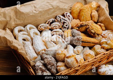 Köstliche Auswahl an frischem Gebäck und Plätzchen in einem rustikalen Korb, mit Puderzucker bestäubt Stockfoto