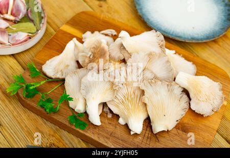 Es gibt einen Haufen roher Austernpilze auf dem Schneidebrett. Stockfoto