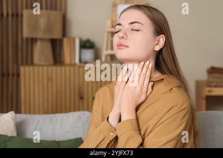 Junge Frau, die zu Hause die Schilddrüse selbst untersucht Stockfoto