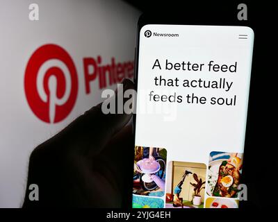 In dieser Abbildung hält eine Person ein Mobiltelefon mit der Webseite des US-amerikanischen Social-Media-Unternehmens Pinterest Inc. Vor dem Firmenlogo. Stockfoto