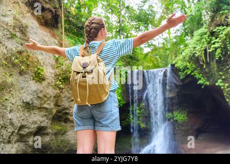 Weibliche Touristenin mit Rucksack, die den Blick auf den fantastischen Wasserfall genießt Stockfoto