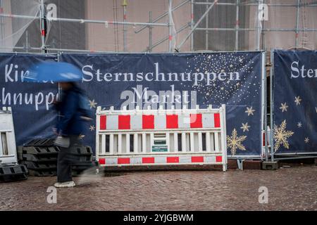 Wiesbaden, Deutschland. November 2024. Eine Frau läuft an einem Banner vorbei, das den Sternschnuppen Markt anpreist. Derzeit laufen Bauarbeiten für den vorweihnachtlichen Sternschnuppen Markt (26. November bis 23. Dezember 2024), der auf dem Schlossplatz und vor der Marktkirche stattfindet. Darlegung: Andreas Arnold/dpa/Alamy Live News Stockfoto