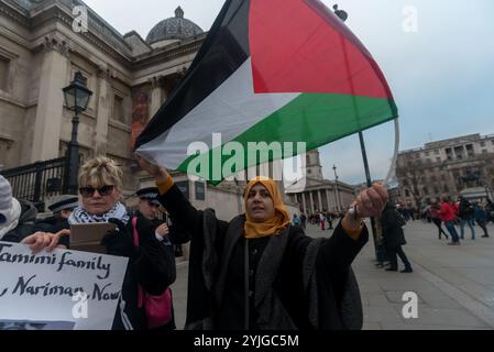 London, Großbritannien. 23. Dezember 2017. Eine Frau hält eine palästinensische Flagge beim Protest auf dem Trafalgar-Platz gegen die Entführung, indem sie am Dienstag, den 19. Dezember, um 4 Uhr morgens die 16-jährige Ahed Tamimi von israelischen Soldaten in ihrem Haus verprügelt und verhaftet und ihre Mutter Nariman Tamimi und ihre Cousine Nour Tamimi verhaftet, um ihre sofortige Freilassung zu fordern. Die beiden jüngeren Frauen hatten zuvor israelische Soldaten in ihrem besetzten Dorf Nabi Saleh geschlagen, als ihr 14-jähriger Cousin von israelischen Soldaten ins Gesicht geschossen wurde. Nachdem der Protest einige Zeit vergangen war, kamen zwei Männer an und versuchten, zu hetzen Stockfoto