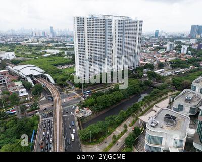 Ein weitläufiger Blick aus der Luft auf Jakarta mit Hochhäusern und einem großen Bahnhof, der Stadtentwicklung und dem geschäftigen städtischen Leben mit Residenti Stockfoto