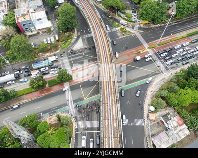 Aus der Vogelperspektive auf eine geschäftige Kreuzung in Jakarta, erhöhte Bahngleise, Verkehr und Stadtstraßen, urbanes Leben in Indonesiens Hauptstadt, Infrastruktur und Stockfoto