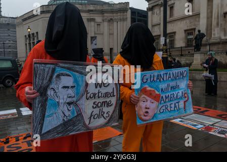 London, Großbritannien. Januar 2018. Auf einem Platz am Trafalgar Square stehen Demonstranten in orangefarbenen Anzügen und schwarzen Kapuzen, die 16 Jahre des illegalen Gefangenenlagers in Guantanamo Bay markieren. Die Namen der 41 verbliebenen Häftlinge wurden vorgelesen, von denen viele auf unbestimmte Zeit ohne Anklage oder Gerichtsverfahren festgehalten wurden, fast alle, die von afghanischen Milizen und dem pakistanischen Militär gegen Geldgelder an die USA verkauft wurden, ohne dass es tatsächlich Beweise für eine terroristische Beteiligung gab, deren Folter aber in geheimen CIA-Gefängnissen auf der ganzen Welt vor der Ankunft in Guantanamo ebenso wie während ihrer gesamten Inhaftung auch ihre Freilassung gibt Stockfoto