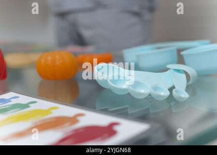 Blaue Messlöffel und Gläser auf einem Glastisch im Sprechzimmer eines Ernährungsberaters. Stockfoto