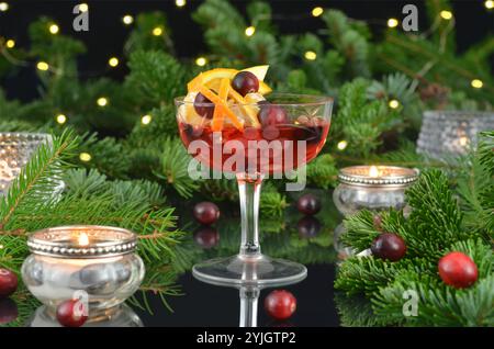 Silvestergetränk in einem Glas mit Lichtern, brennenden Kerzen und grünen Zweigen auf dunklem Hintergrund. Stockfoto
