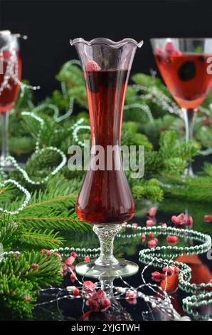 Silvester: Drei rote Getränke in Gläsern mit Weihnachtszweigen dekoriert; Bokeh, schwarzer Hintergrund. Stockfoto