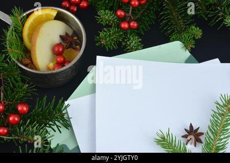 Weihnachtsstanze in einem Topf, einer Karte und einem Umschlag; weißes Blatt Papier zum Füllen mit Inhalt, dekoriert mit grünen Zweigen und roten Preiselbeeren. Stockfoto