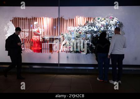 Weihnachtseinkäufer genießen die John Lewis 2024 Weihnachtsfenster zu Beginn der Feiertage entlang der Oxford Street, Großbritanniens geschäftigster Straße. Stockfoto