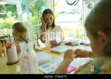 Die Lehrerin in der Werkstatt hat zwei Mädchen beigebracht, wie man ein Thermomosaik zusammenbaut Stockfoto